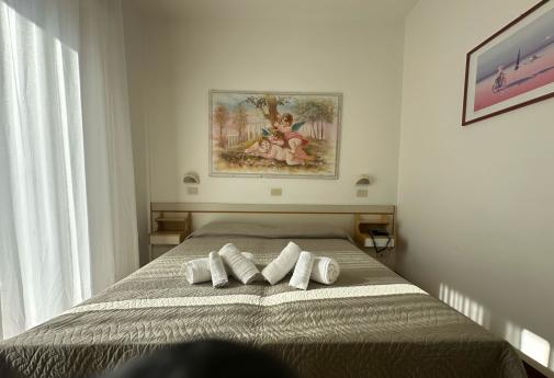 Camera accogliente con letto matrimoniale, quadri e luce calda del sole.